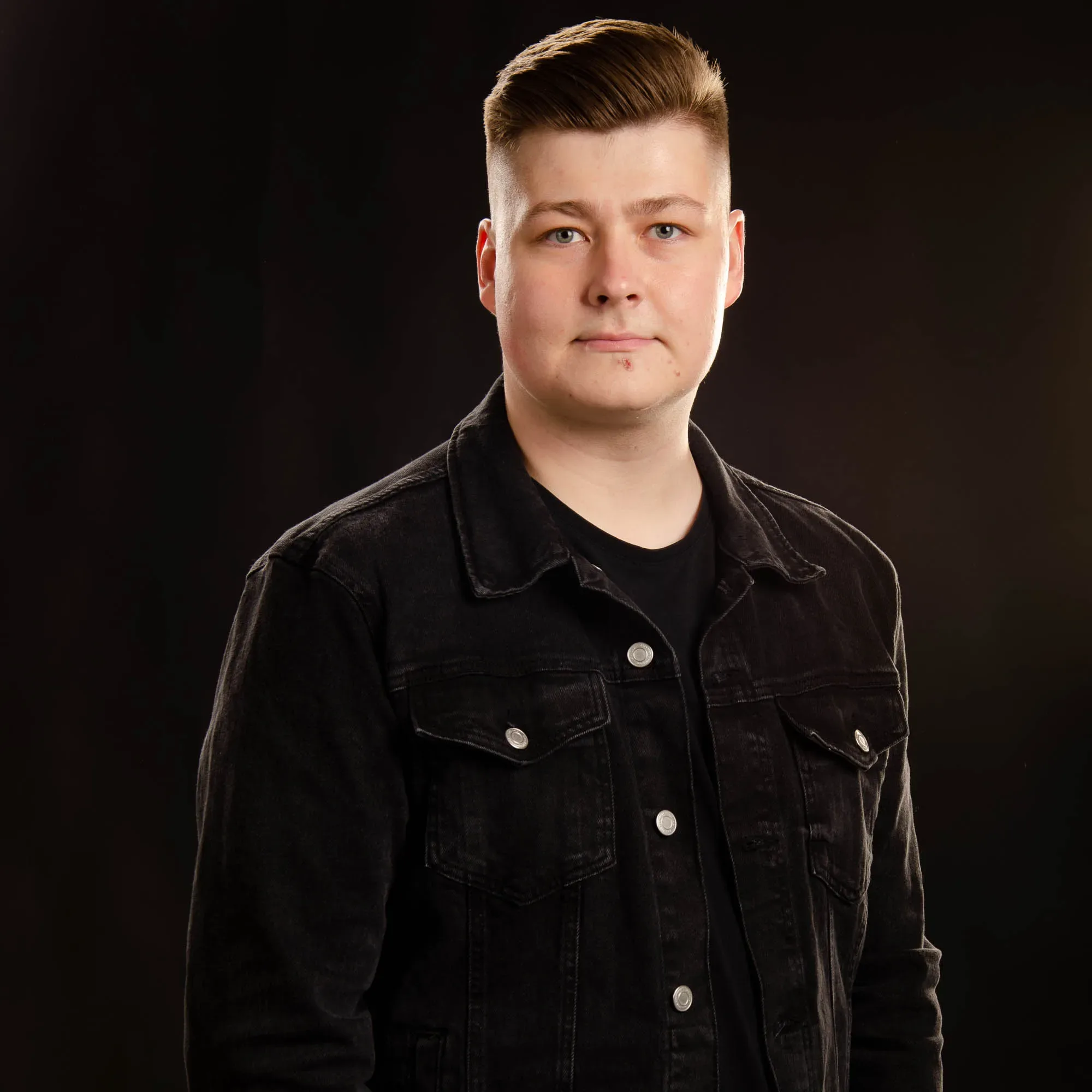 Eeli Arola tummassa farkkutakissa mustaa taustaa vasten